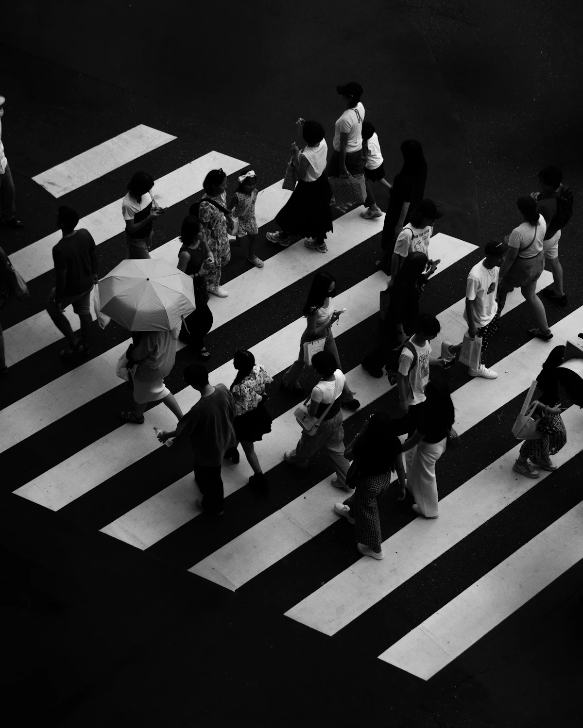 Piétons vus en plongée sur un passage clouté, en noir et blanc.