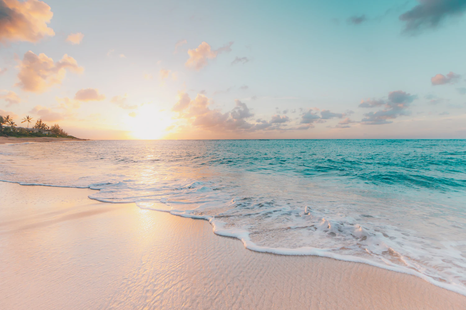 Vagues sur une plage de sable clair au coucher du soleil.